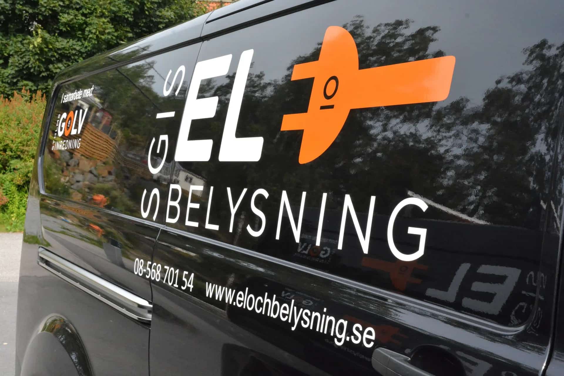 Hantverkare med verktygsbälte och verktyg, svart långärmad tröja och shorts